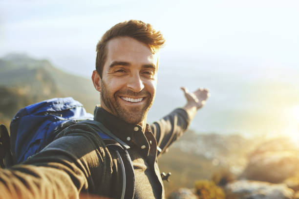 Shot of a young man taking selfies while hiking up a mountain